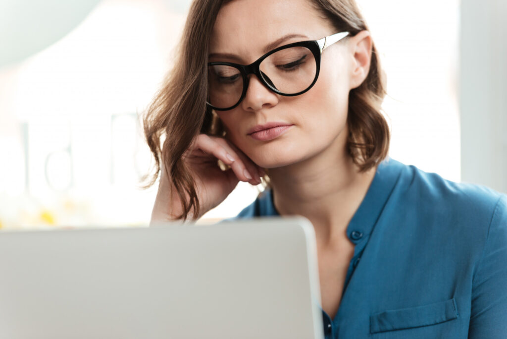 Kobieta w okularach do komputera, skupiona na pracy przy ekranie – oprawki dobrane z myślą o komforcie widzenia i ochronie wzroku. Okulary do komputera to wsparcie dla Twojego wzroku w pracy biurowej – zmniejszają zmęczenie oczu i zwiększają komfort codziennego widzenia.